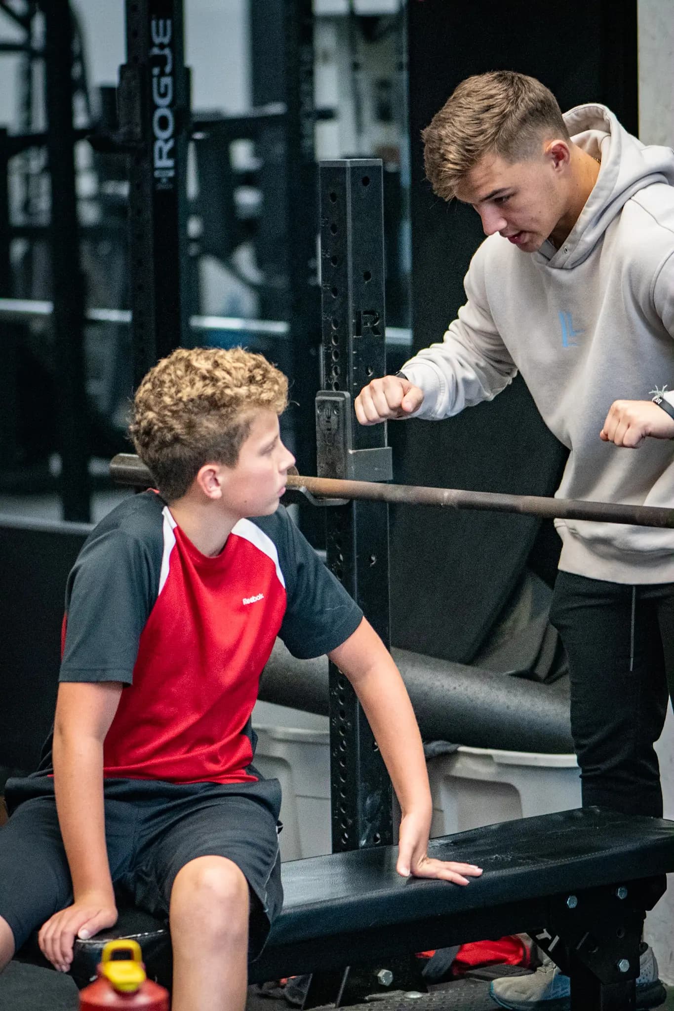 An Aspire coach teaching a young athlete at the barbell